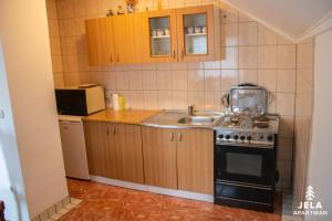 a small kitchen with a stove and a sink at Apartman Jela in Kupres +7 photos
