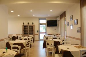 a restaurant with white tables and chairs and a flat screen tv at Hotel la locanda di montecatone in Imola