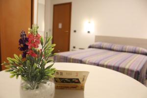 a vase with flowers on a table with two beds at Hotel la locanda di montecatone in Imola