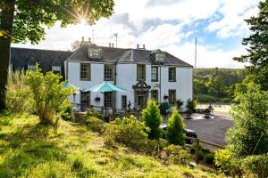 uma grande casa branca numa colina com árvores em Banchory Lodge Hotel em Banchory