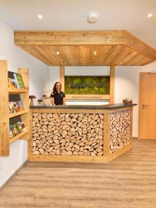 a person standing behind a counter with a pile of wood at Traditions-Gasthaus Bayrischer Hof in Leutkirch im Allgäu