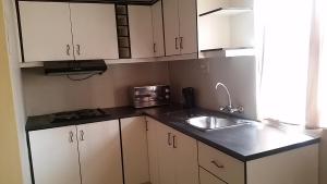 a small kitchen with white cabinets and a sink at Dolphin Guest House in Walvis Bay