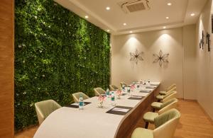 - une longue table dans une pièce dotée d'un mur vert dans l'établissement Click Hotel Bangalore - International Airport, à Devanhalli