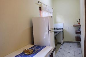 a kitchen with a white refrigerator and a stove at CHALÉS e SUITES PORTO SEGURO in Maresias