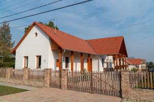 Kun Pista Vendégház في Vértesboglár: منزل أبيض صغير مع سور خشبي