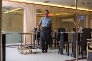 a woman standing in a restaurant with a cart at Euro Hotel and Apartments in Dar es Salaam