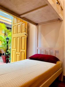 a bedroom with a bed and a yellow door at Easy Hostels in Panaji