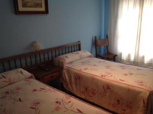 1 dormitorio con 2 camas, mesa y ventana en Hostal Los Amigos, en Olivenza