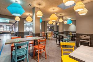 a dining room with tables and chairs and lights at a&o Hamburg Hauptbahnhof in Hamburg +47 photos