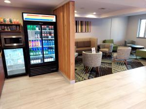 a restaurant with a drink cooler and tables and chairs at Holiday Inn Express Maspeth, an IHG Hotel in Queens