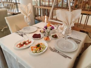 a white table with plates of food on it at Natur Pur Hotel Unterpichl in Ultimo