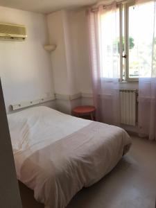 Un dormitorio con una cama blanca y una ventana. en Bora, en Béziers