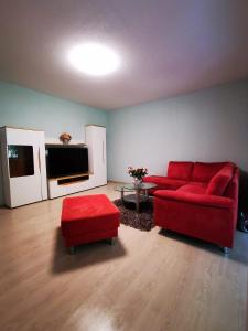 sala de estar con sofá rojo y TV en Ferienhaus/Ferienwohnung Fam. Manthey en Harrendorf
