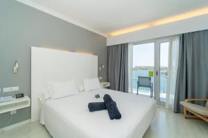 a bedroom with a white bed with a black tie on it at ARTIEM Carlos - Adults Only in Es Castell