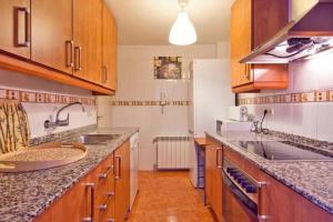 a kitchen with wooden cabinets and granite counter tops at Junto a Vielha Apartamento Gausac in Gausach