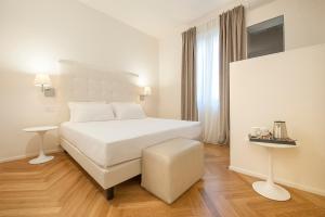 a white bedroom with a white bed and a stool at Asisium Boutique Hotel in Assisi