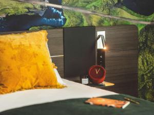 a bed with a yellow pillow and a clock on a table at Novotel Paris Porte Versailles in Paris