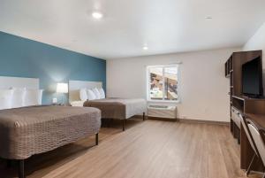 a hotel room with two beds and a flat screen tv at WoodSpring Suites Fort Mill in Fort Mill