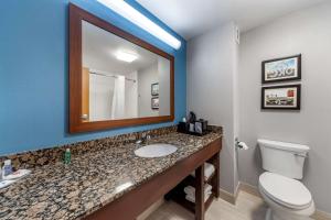 a bathroom with a sink and a toilet and a mirror at Garner Oklahoma City - Quail Springs, an IHG Hotel in Oklahoma City