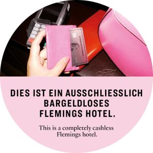 a person holding a cell phone next to a book at Flemings Selection Hotel Frankfurt-City in Frankfurt