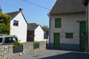 una casa con puertas verdes y una valla de piedra en Les gîtes du Broukay - Alouette, en Bassenge