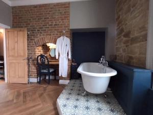 a bathroom with a white bath tub and a brick wall at Castle View Bed and Breakfast in Morpeth