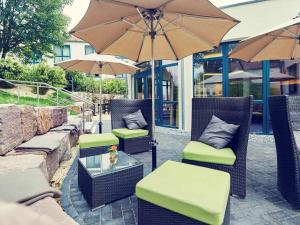 een patio met stoelen en tafels met parasols bij Mercure Tagungs- & Landhotel Krefeld in Krefeld