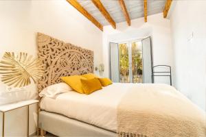 a white bedroom with a large bed with yellow pillows at Casa 95 Sevilla in Seville