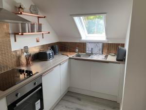 a kitchen with white cabinets and a sink and a window at The Clachan Flat in Rosneath