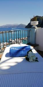 a bed with a blue blanket and flowers on a balcony at Relais Maresca Luxury Small Hotel & Terrace Restaurant in Capri