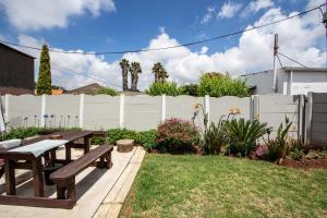 a backyard with two picnic tables and a white fence at WILLOW GUEST HOUSE in Boksburg