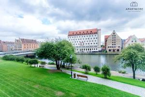 a park with benches next to a river with buildings at Rezydencja Wintera i Lastadia by Apartmore in Gdańsk