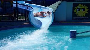 a man is sliding down a water slide in a pool at Apollo Self Catering in Vredenburg