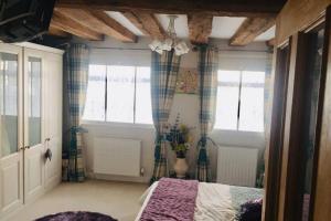 a bedroom with a bed and two windows at Potters Court A Hidden Gem in Tewkesbury