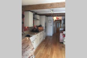 a kitchen with white cabinets and a wooden floor at Potters Court A Hidden Gem in Tewkesbury