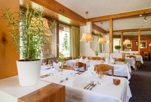 ein Restaurant mit weißen Tischen und einer Topfpflanze in der Unterkunft T3 Hotel Mira Val in Flims