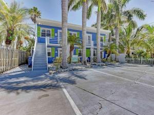 ブレイデントン・ビーチにあるIdeal beach hideaway pool condo located between the island marina and beachのヤシの木が目の前に広がる青緑の建物
