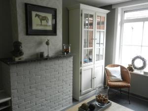 a living room with a brick fireplace and a chair at Holiday Home Juliette in Poperinge