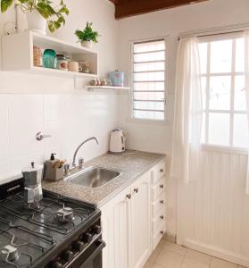 a white kitchen with a sink and a stove at Loft Amarillo in Tandil