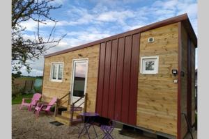 una casa pequeña con puerta roja y sillas rosas en Tiny house, en Amécourt