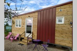 a tiny house with a red roof and purple chairs at Tiny house in Amécourt