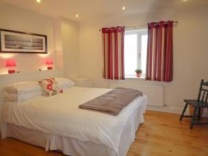 a bedroom with a bed and a window with red curtains at Fourteens Holiday Home Ballinskelligs in Ballinskelligs