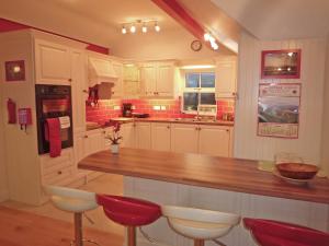 a large kitchen with a wooden counter and red stools at Fourteens Holiday Home Ballinskelligs in Ballinskelligs