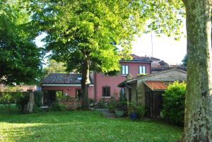 una casa rosa con un albero in cortile di La Casa di Marina a Ferrara