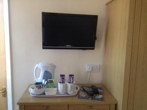 a table with a coffee maker and a tv on a wall at Arcadia Guest House in Weymouth