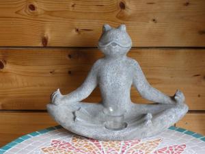 une statue d'une grenouille assise dans une pose de méditation avec une tasse dans l'établissement Au Crapaud Charmant, à Labuissière