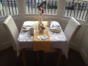 a table with a vase of flowers on top of it at Arcadia Guest House in Weymouth +28 photos