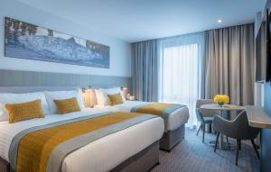 a hotel room with two beds and a desk at Maldron Hotel Glasgow City in Glasgow