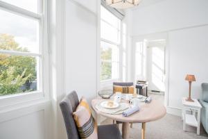 a room with a table and chairs and windows at 50 London Road - By Luxury Apartments in Cheltenham