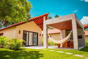 uma casa com uma rede em frente em Costa Dourada Village em Maragogi